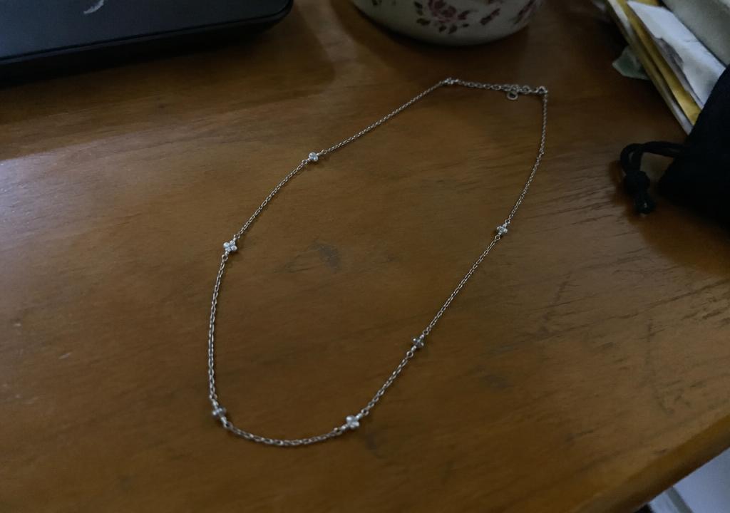 Silver chain photographed on a cluttered table before Yuvexa enhancement